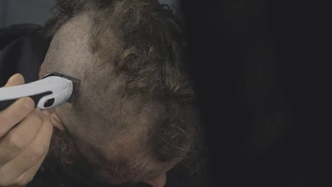 A man with a beard shaves his head with an electric trimmer Stock Footage 120393178