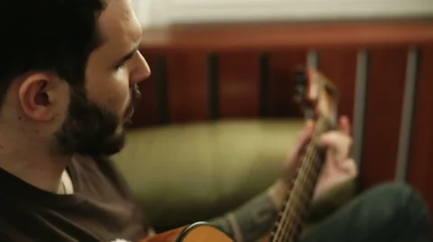 A man with a beard singing and  playing the guitar Stock Footage 61886760