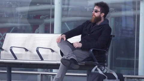 Man with Beard sit on bench outside airport Stock Footage 74166762