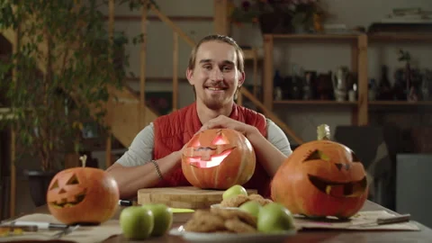 A man with a beard sits at a table with lamps for halloween. On smiling and Stock Footage 163127800