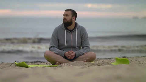 Man with Beard Sitting on Beach and Looking Around - Wide Shot Stock Footage 130737522