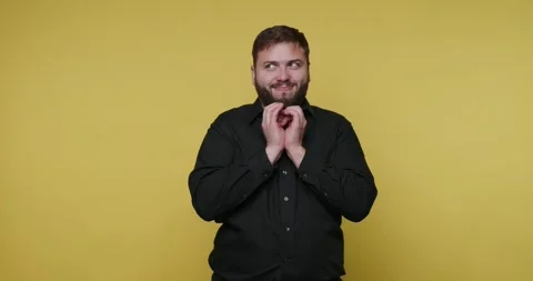 Man with beard smiles and plots something in front of a yellow background Vídeo Stock 326789765