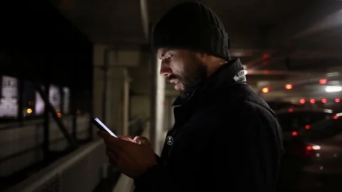 Man with a beard smiling writes a letter on the phone at night Stock Footage 129333817