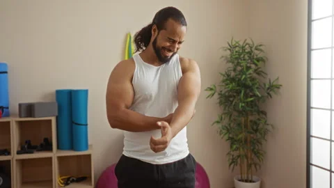 Man with a beard in a spa room holding his elbow with a concerned look, sur.. Stock Footage 294595251