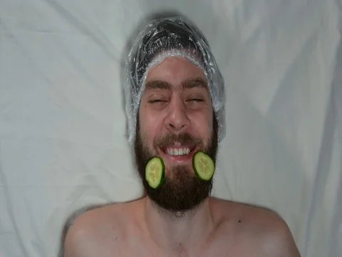 Man with a beard in a spa salon. A man is made a mask of cucumbers. Stock Footage 121085529