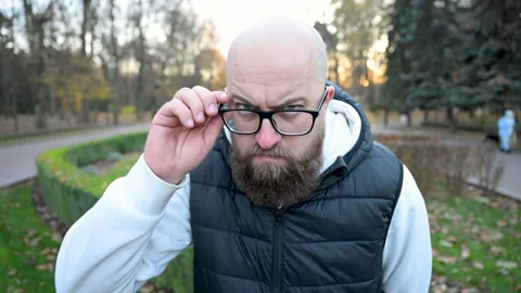 Man with beard standing in park maze during autumn evening, expressing serious Stock Footage 346709553