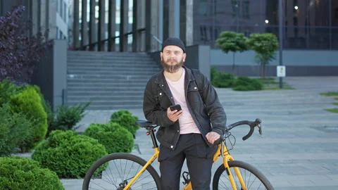 Man with beard standing with yellow bicycle near modern building. Stock Footage 228918023