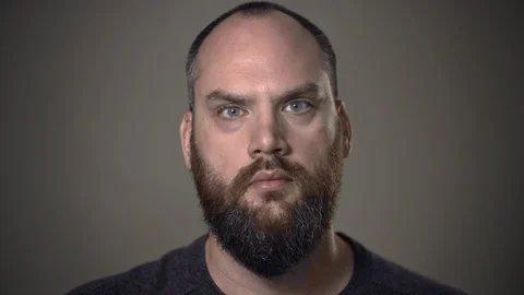 Man with beard stares expressionless, feeling sorrowful or depressed. Stock Footage 129061275