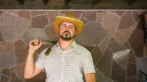 A man with a beard in a straw hat with clippers on his shoulder 4K Stock Footage 115550066