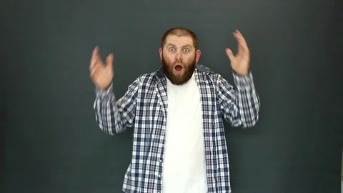 A man with a beard takes his head and opens his mouth in surprise. Video stock 155757504