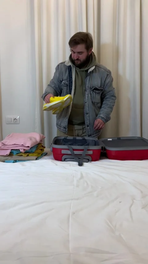 Man with beard takes out clothes from red suitcase Stock Footage 308127300