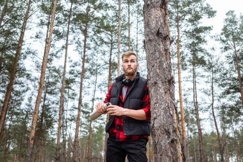 Man with beard taking rest in forest after walk, is drinking hot coffee Stock Photos