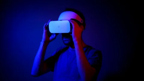 A man with a beard in a VR helmet interacts with virtual reality and views media Stock Footage 121387240