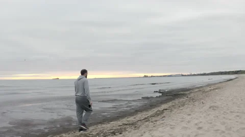 Man with Beard Walking by the Beach at Dusk - Wide Dolly Shot Stock Footage 130730367