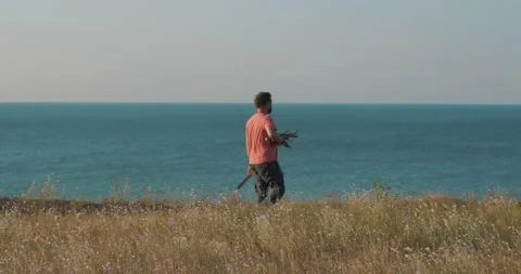 A man with a beard walks along a cliff against the background of the sea Stock Footage 135417546