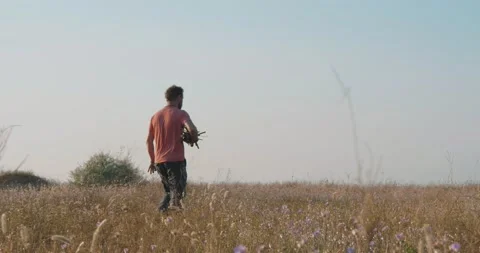 A man with a beard walks in the field, holding tree branches under his arm Stock Footage 135417557