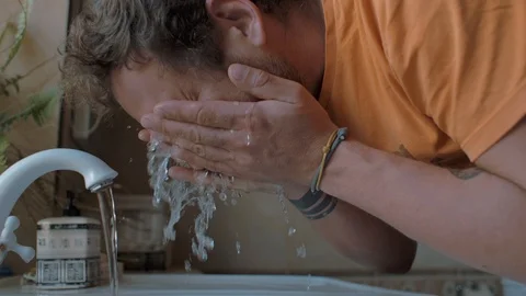 Man with a beard washes his face with water while standing near the washbasin Stock Footage 118137793