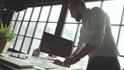 Man with beard works against the background of large panoramic window 스톡 동영상 87968659