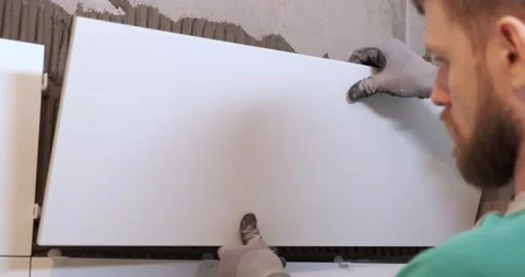 Man with beard works at construction site, puts tiles on wall in bathroom, works Stock Footage 130366476