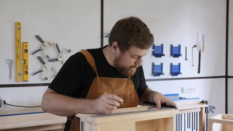 A man with a beard works in his workshop. Profession carpenter. A man works with Stock Footage 113995311