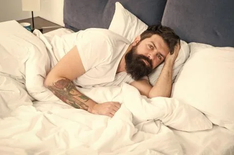 Man bearded hipster having problems with sleep. Guy lying in bed try to relax Stock Photos