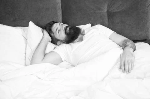 Man bearded hipster having problems with sleep. Guy lying in bed try to relax Stock Photos