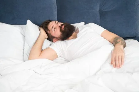 Man bearded hipster having problems with sleep. Guy lying in bed try to relax Stock Photos