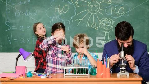 Man bearded teacher and pupils with test tubes in classroom. Observe reaction Stock Photos