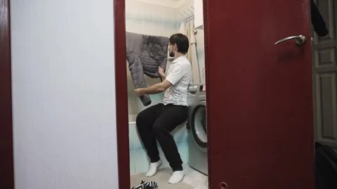 Man beating down jacket on drying rack to evenly distribute down after washing. Vídeo Stock 330543866