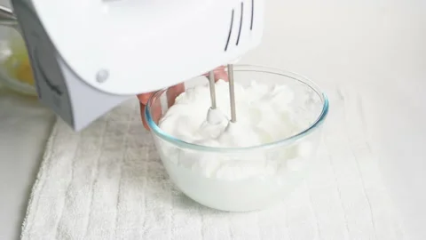 A man beats egg white with a mixer in a transparent bowl in the kitchen. Stock Footage 231865144