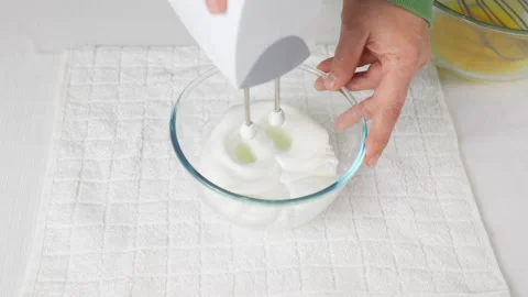 A man beats egg white with a mixer in a transparent bowl in the kitchen. Stock Footage 231865763