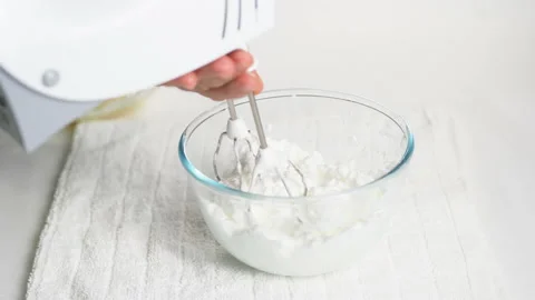 A man beats egg white with a mixer in a transparent bowl in the kitchen. Stock Footage 231865998