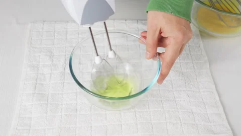 A man beats egg white with a mixer in a transparent bowl in the kitchen. Stock Footage 231866599