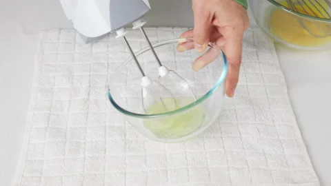 A man beats egg white with a mixer in a transparent bowl in the kitchen. Stock Footage 231866864