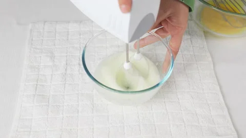 A man beats egg white with a mixer in a transparent bowl in the kitchen. Stock Footage 231867148
