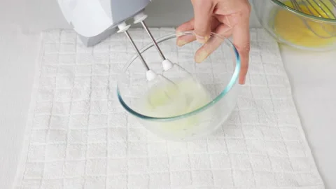 A man beats egg white with a mixer in a transparent bowl in the kitchen. Stock Footage 231867690