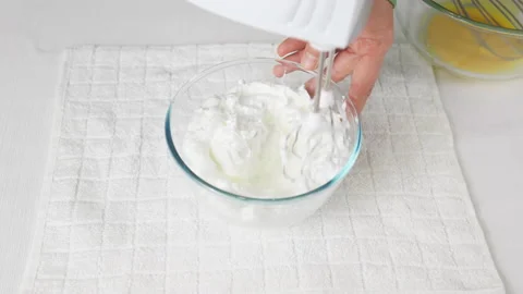 A man beats egg white with a mixer in a transparent bowl in the kitchen. Stock Footage 231868209