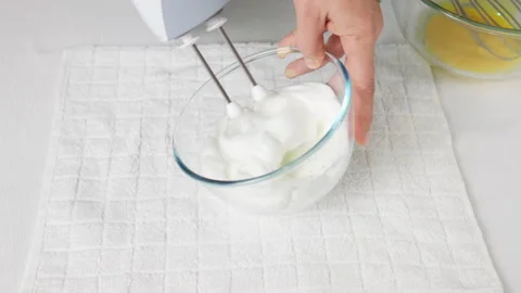 A man beats egg white with a mixer in a transparent bowl in the kitchen. Stock Footage 231868580