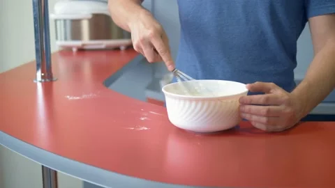 A man beats eggs with flour. make dessert in the home kitchen Stock Footage 130460852