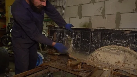 Man beats with a hammer on the rusty car body Stock Footage 80929012