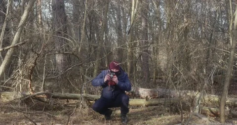 A man in a beautiful pine forest takes pictures of squatting on a film camer 스톡 동영상 166439274