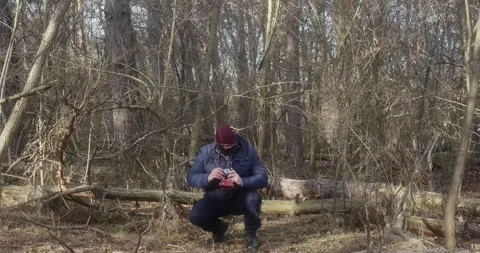 A man in a beautiful pine forest takes pictures of squatting on a retro film Vídeos de archivo 166439286