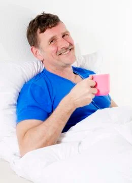 Man in bed with cup Stock Photos