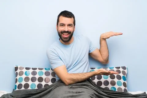 Man in bed holding copyspace to insert an ad Stock Photos
