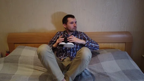 Man on the bed looks Virtual Reality Headset. Hotel or home bedroom Stock Footage 103330103