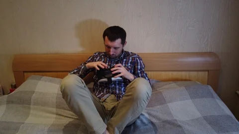 Man on the bed looks Virtual Reality Headset. Hotel or home bedroom Stock Footage 103331198