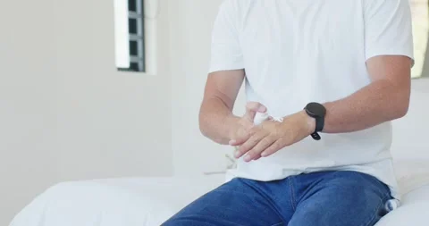 Man on bed is pressing white pump, releasing foam, rubbing hands and Stock Footage 344645181