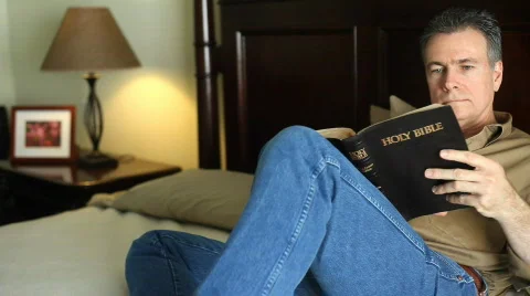 Man bed reading bible Stock Footage