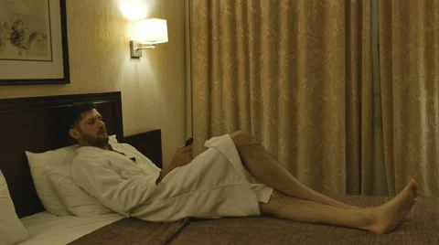 The man on the bed with the remote Stock Footage 64764660