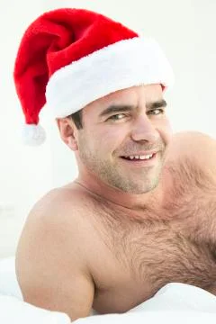 Man in bed with santa hat Stock Photos